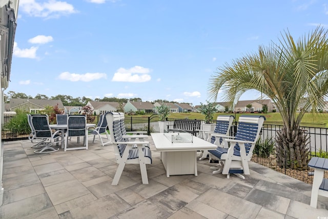 view of patio featuring fence, a residential view, outdoor dining space, and an outdoor fire pit