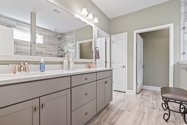 full bath with a sink, double vanity, tiled shower, and visible vents