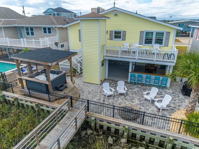 back of house with a hot tub, a patio area, stairs, and a deck