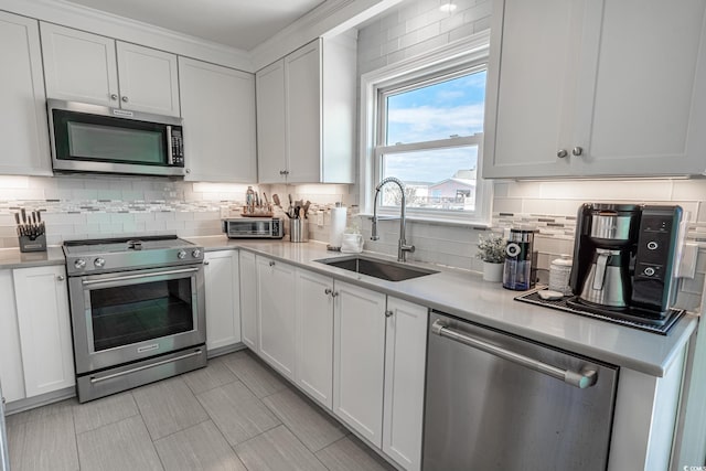 kitchen featuring appliances with stainless steel finishes, a sink, tasteful backsplash, and light countertops