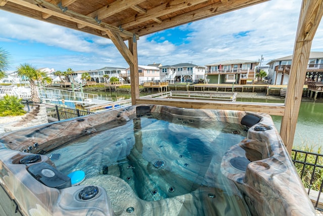 view of swimming pool with a water view, a residential view, and a hot tub