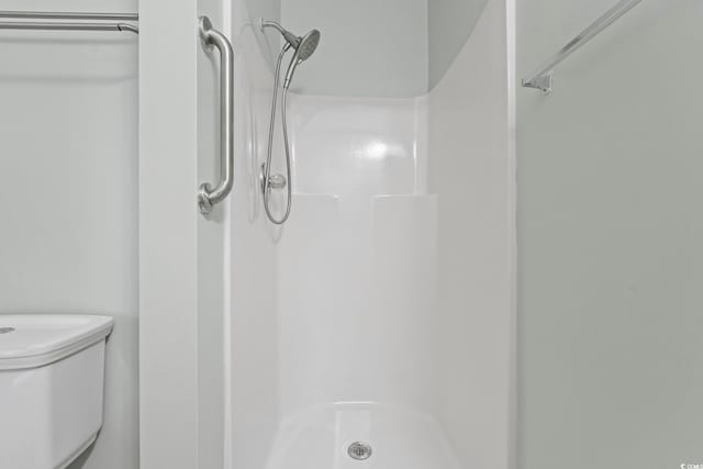 full bathroom featuring a shower stall and toilet