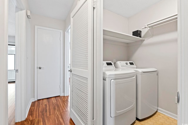 laundry area featuring baseboards, laundry area, wood finished floors, and washer and clothes dryer