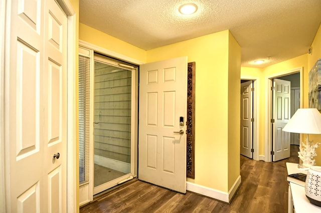 foyer with a textured ceiling, dark wood finished floors, and baseboards