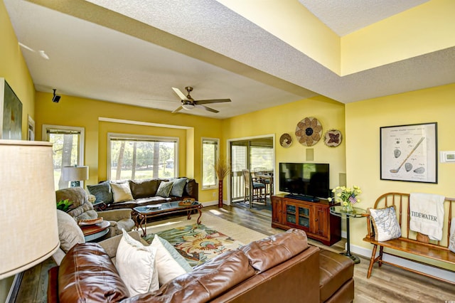 living area with a ceiling fan, baseboards, and wood finished floors