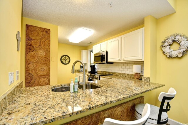 1401 Lighthouse Dr Unit 4226, North Myrtle Beach, SC 29582 - kitchen with light stone countertops, a sink, stainless steel appliances, white cabinetry, and decorative backsplash