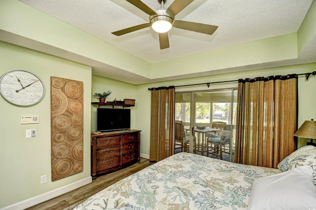 bedroom with baseboards, a textured ceiling, wood finished floors, and access to exterior
