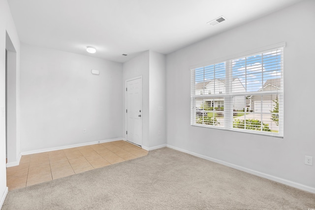 spare room with carpet floors, baseboards, tile patterned flooring, and visible vents