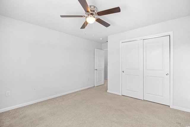 unfurnished bedroom with baseboards, a ceiling fan, a closet, and light colored carpet