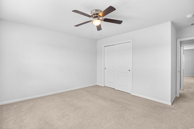 unfurnished bedroom featuring baseboards, a ceiling fan, a closet, and light colored carpet
