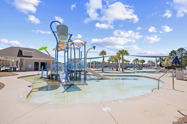 pool with a patio, a water play area, a water slide, and playground community