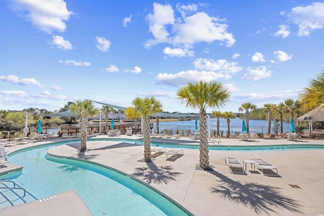 community pool featuring a water view, fence, and a patio area