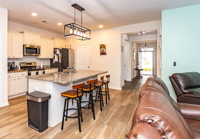 40 Parkside Dr, Pawleys Island, SC 29585 - kitchen with stainless steel appliances, a sink, a kitchen breakfast bar, a kitchen island with sink, and light wood-type flooring