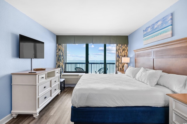bedroom featuring baseboards, access to outside, and wood finished floors
