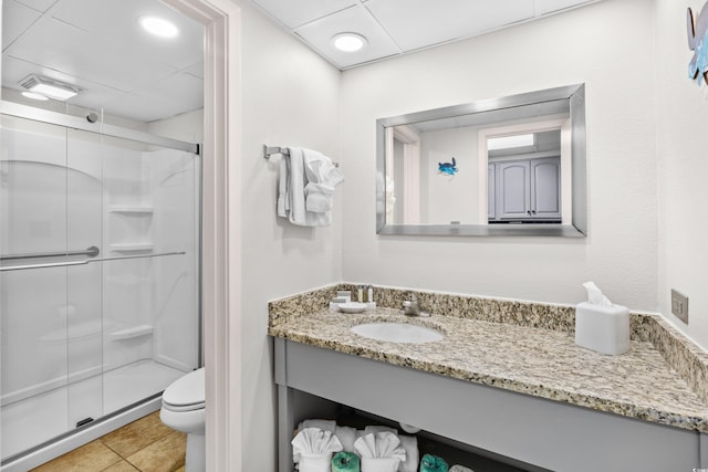 bathroom featuring vanity, toilet, a drop ceiling, tile patterned floors, and a shower stall