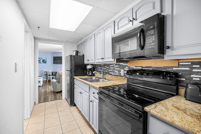 kitchen featuring backsplash, light tile patterned flooring, a sink, and black appliances