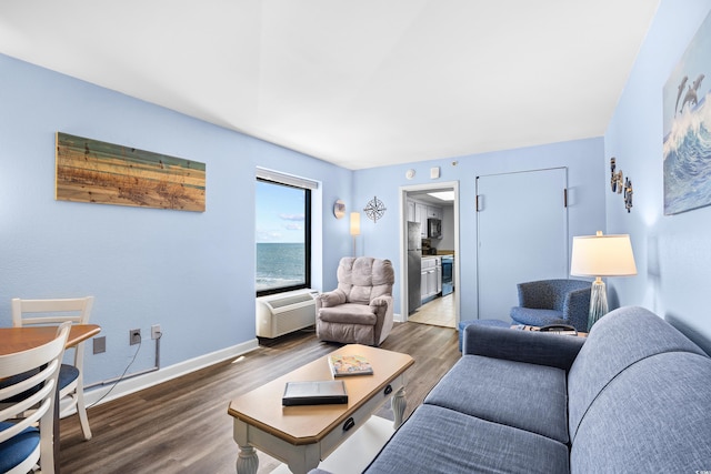 living area with baseboards, a wall unit AC, and wood finished floors
