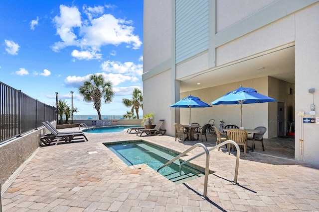 community pool featuring fence, a patio, and a hot tub