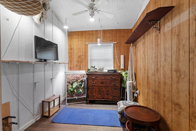interior space featuring wood walls, wood finished floors, and ceiling fan