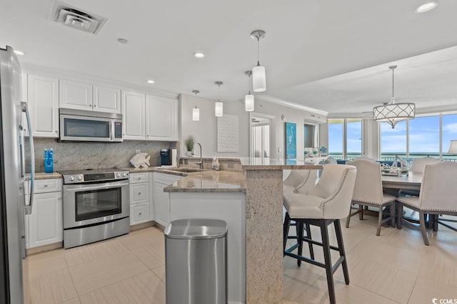 kitchen featuring appliances with stainless steel finishes, a peninsula, a sink, white cabinets, and crown molding
