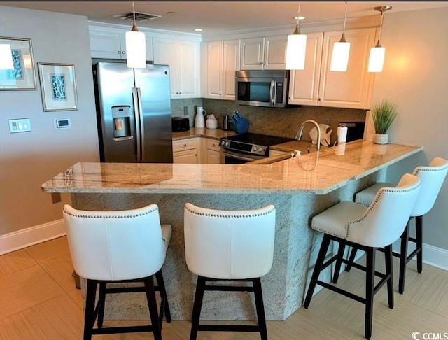 kitchen featuring appliances with stainless steel finishes, baseboards, a peninsula, and light stone counters