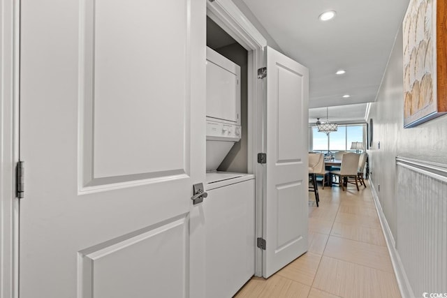 corridor featuring stacked washer and clothes dryer, recessed lighting, baseboards, and light tile patterned flooring