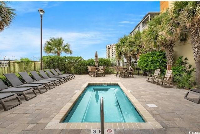 community pool featuring outdoor dining area, a patio, and fence