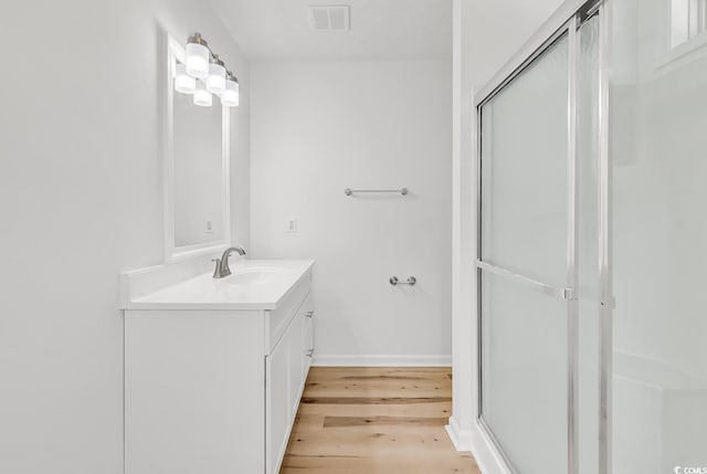 9616 Sullivan Dr, Murrells Inlet, SC 29576 - bathroom with visible vents, vanity, wood finished floors, baseboards, and a shower with shower door