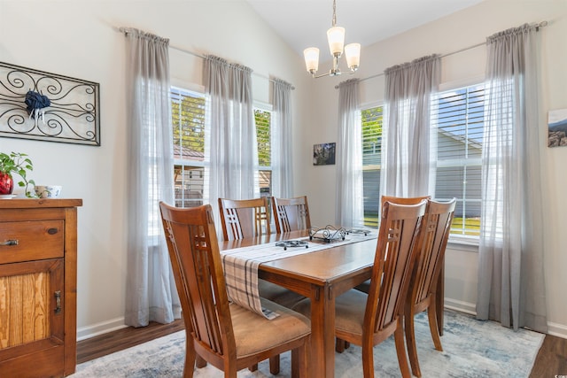 dining space with light wood-type flooring, a chandelier, lofted ceiling, and baseboards