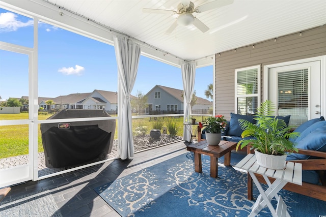 sunroom / solarium with a ceiling fan, a residential view, and plenty of natural light