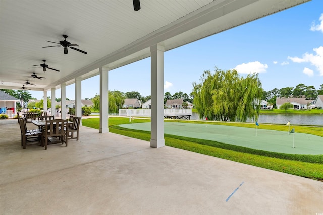 view of patio / terrace with a putting area, a ceiling fan, a residential view, a water view, and outdoor dining space