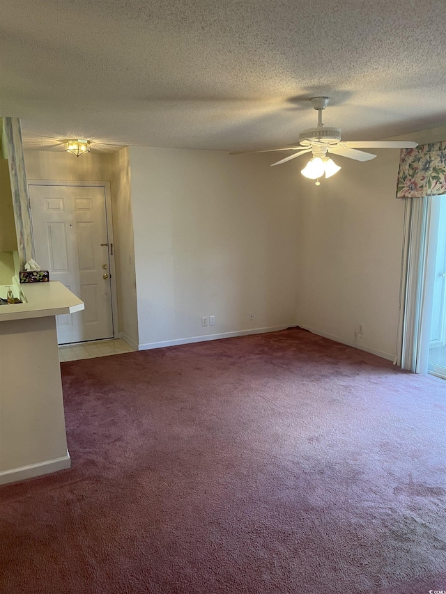 empty room featuring baseboards, a ceiling fan, a textured ceiling, and light carpet