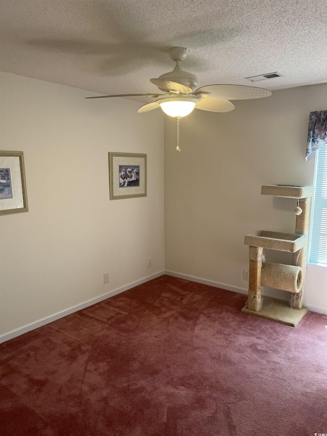 empty room with visible vents, a textured ceiling, carpet, and ceiling fan