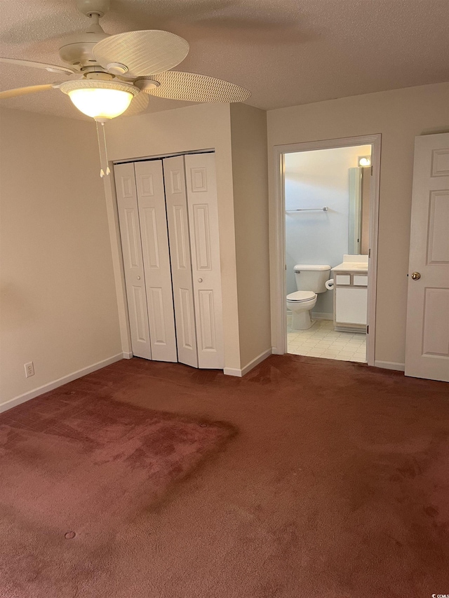 unfurnished bedroom featuring carpet flooring, ensuite bath, a ceiling fan, baseboards, and a closet