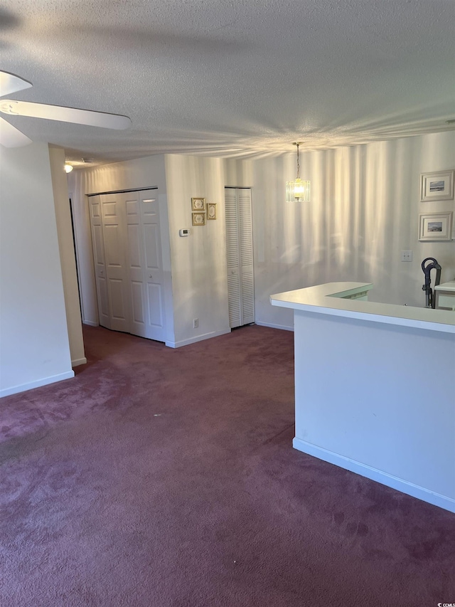 interior space with carpet floors, baseboards, and a textured ceiling