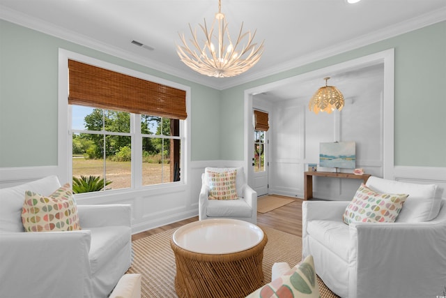 sitting room featuring an inviting chandelier, ornamental molding, visible vents, and light wood-style floors