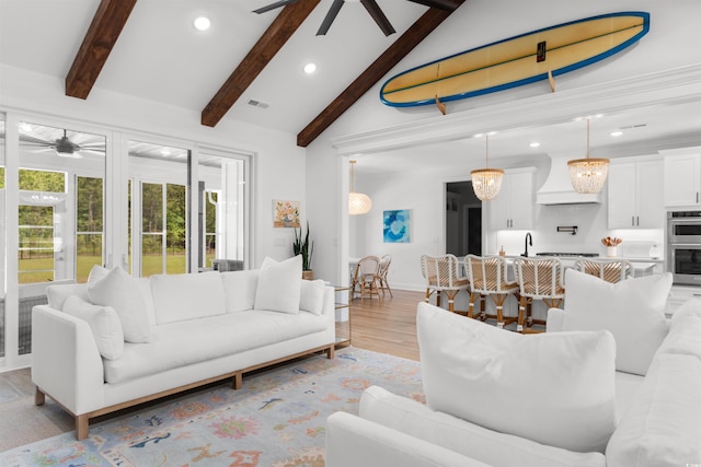 living area with a ceiling fan, vaulted ceiling with beams, and a healthy amount of sunlight