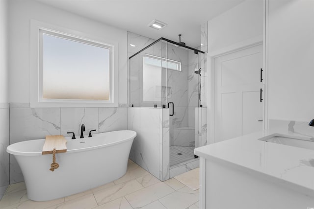 full bath featuring a sink, a marble finish shower, a freestanding tub, and marble finish floor