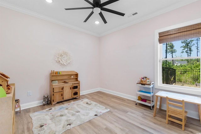 interior space with crown molding, a ceiling fan, visible vents, and wood finished floors