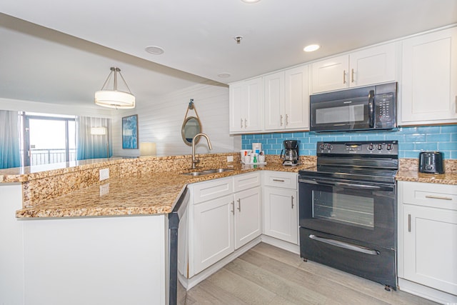 kitchen featuring a sink, a peninsula, white cabinetry, backsplash, and black appliances