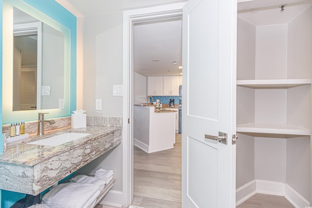 bathroom with baseboards, a sink, wood finished floors, and tasteful backsplash