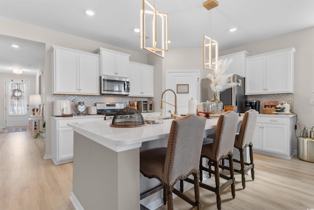 315 Cattle Drive Cir, Myrtle Beach, SC 29588 - kitchen with appliances with stainless steel finishes, backsplash, light wood-type flooring, a breakfast bar, and recessed lighting