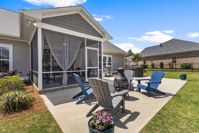 view of patio / terrace featuring a hot tub, fence, and a sunroom