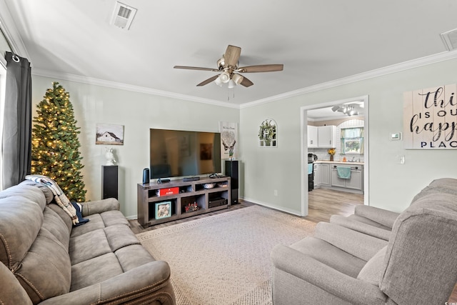 living room featuring ceiling fan, ornamental molding, and baseboards