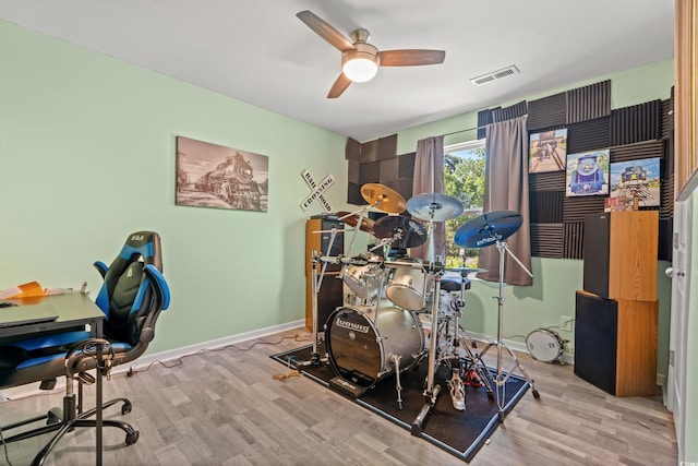 workout room with wood finished floors, a ceiling fan, and baseboards