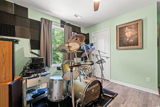 exercise area featuring wood finished floors, baseboards, and a ceiling fan