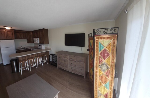 300 47th Ave S Unit 1E, North Myrtle Beach, SC 29582 - kitchen featuring white appliances, a sink, wood finished floors, a breakfast bar area, and a peninsula