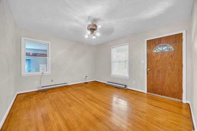 foyer entrance featuring a baseboard heating unit, a ceiling fan, light wood-type flooring, and baseboards