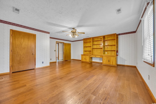 unfurnished living room with wallpapered walls, a ceiling fan, light wood-style flooring, crown molding, and plenty of natural light