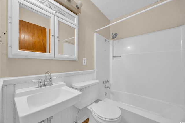 full bathroom with a sink, wainscoting,  shower combination, and toilet